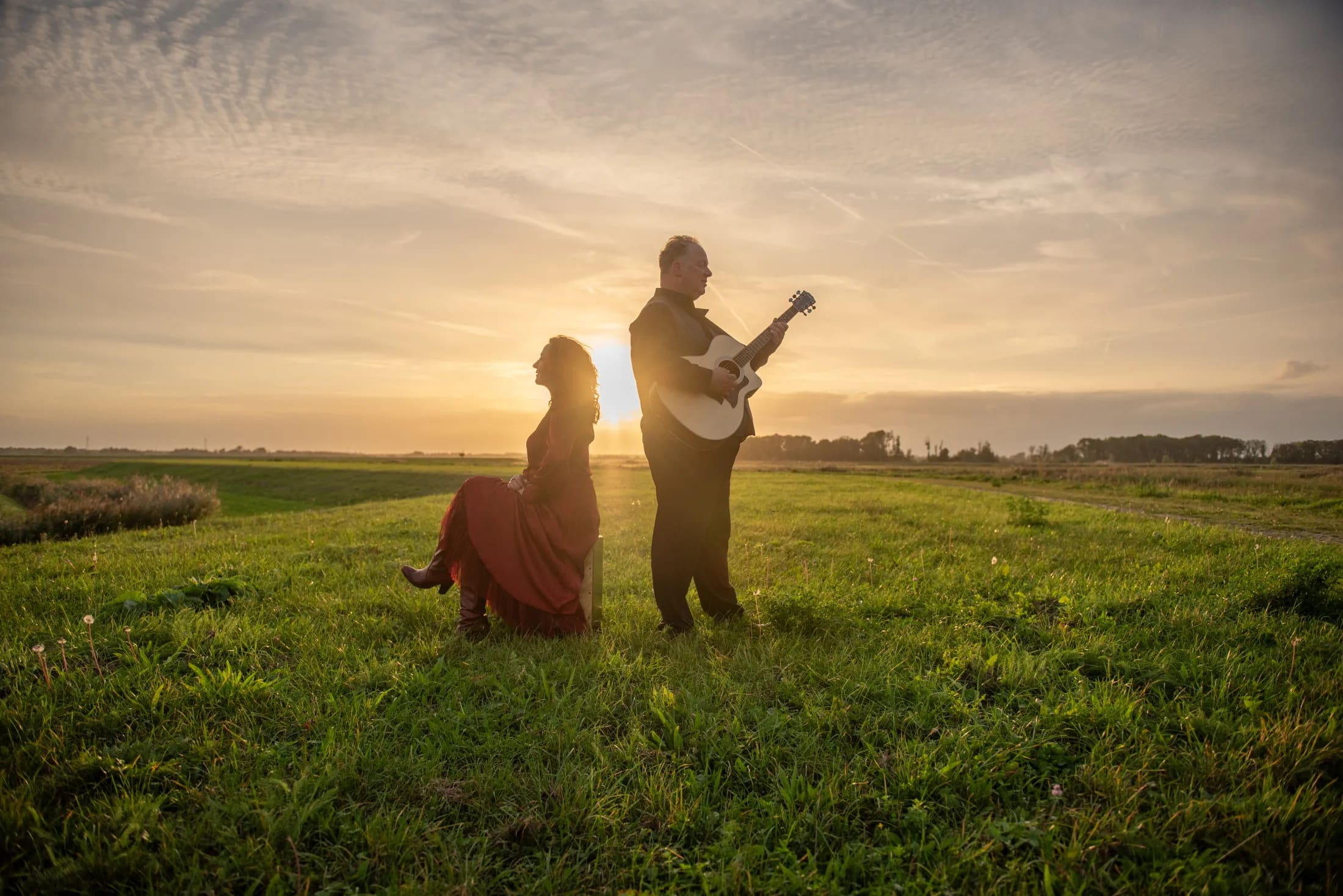Arthur en Bettina in tegenlicht in het veld, met gitaar en warme avondzon